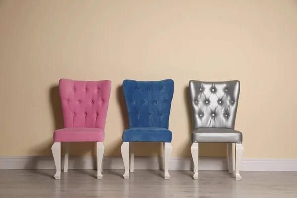 Distintas sillas elegantes y elegantes cerca de la pared beige — Foto de Stock