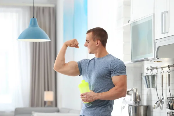 Jovem atlético com batido de proteína na cozinha — Fotografia de Stock
