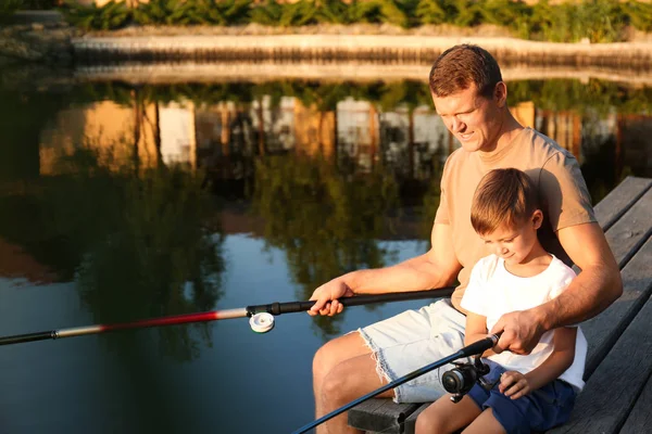 Dad and son fishing together on sunny day