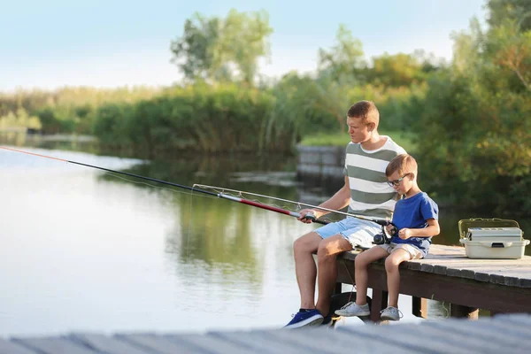 Dad and son fishing together on sunny day