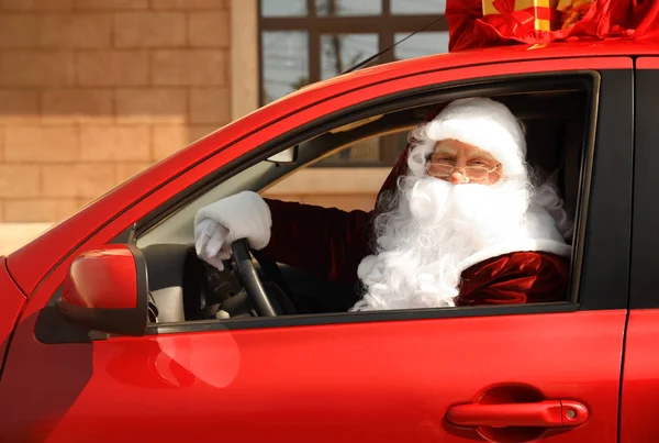 Autentico Babbo Natale con borsa piena di regali sul tetto guida auto moderne, all'aperto — Foto Stock