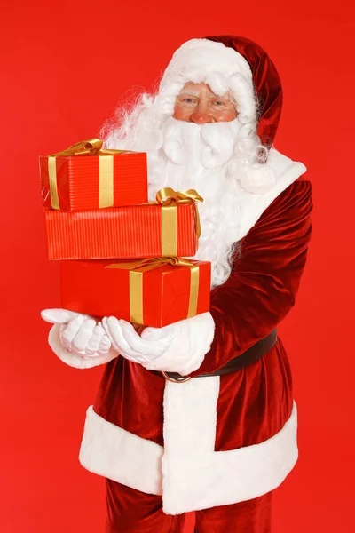 Authentieke Kerstman met geschenkdozen op rode achtergrond — Stockfoto