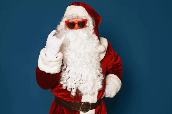 Auténtico Santa Claus con gafas de sol sobre fondo azul —  Fotos de Stock