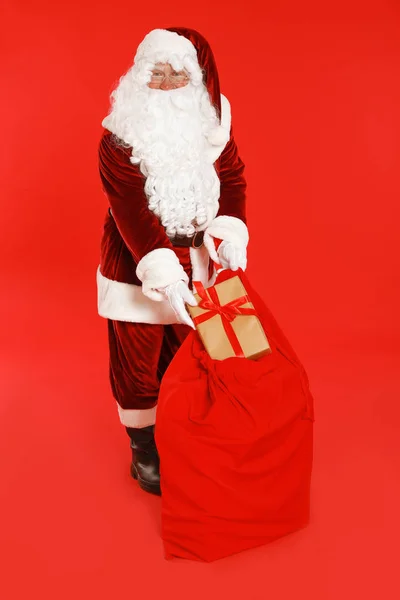 Autêntico Papai Noel com saco e presente no fundo vermelho — Fotografia de Stock