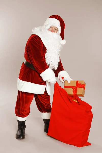 Auténtico Santa Claus con saco y regalo sobre fondo gris —  Fotos de Stock