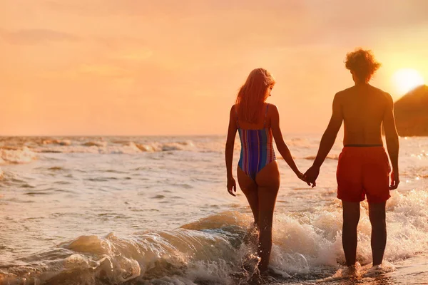 Jovem de biquíni e namorado na praia ao pôr-do-sol. Casal encantador — Fotografia de Stock