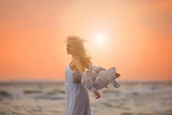 Beautiful young woman on beach at sunset — Stock Photo, Image
