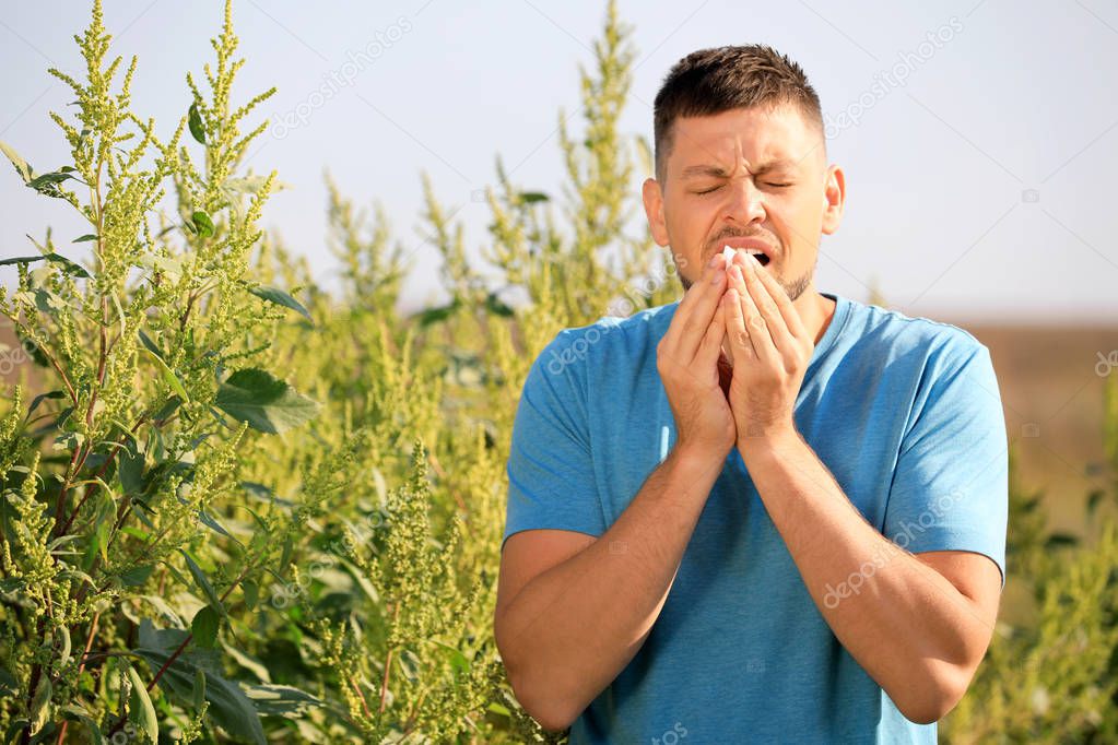 Man suffering from ragweed allergy outdoors on sunny day