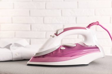 Tuğla duvara karşı gemide Modern elektrikli demir ve katlanmış gömlek