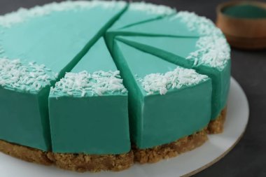 Koyu gri masa üzerinde dilimlenmiş lezzetli spirulina cheesecake, closeup görünümü