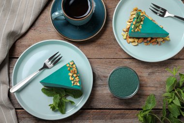 Ahşap masa üzerinde lezzetli spirulina cheesecake ile Düz lay kompozisyon