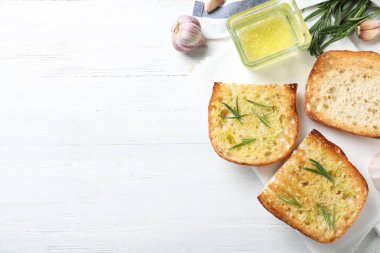 Beyaz ahşap masa üzerinde sarımsak ve ot ile tost ekmek Dilimleri, düz yatıyordu. Metin için alan