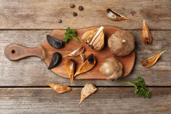 Flat lay composition with black garlic on wooden table