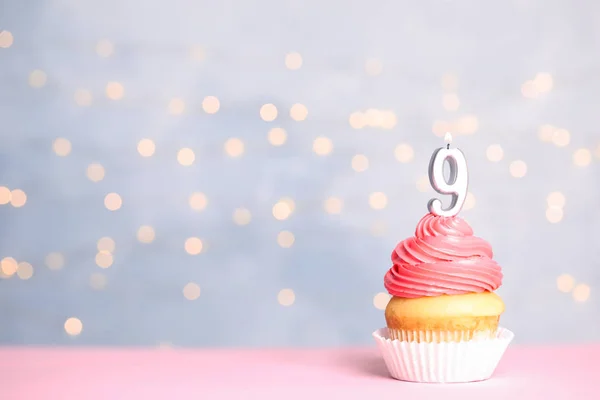 Cupcake d'anniversaire avec numéro neuf bougie sur la table contre les lumières festives, espace pour le texte — Photo