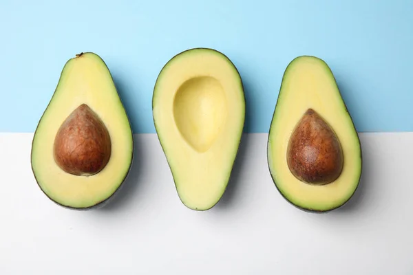 Geschnitten frische reife Avocados auf farbigem Hintergrund, flache Lage — Stockfoto