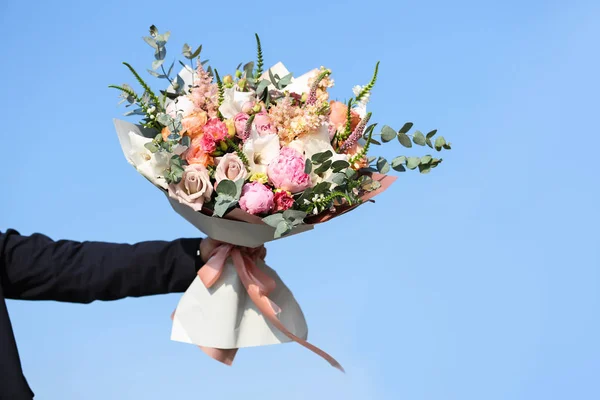 Man holding beautiful flower bouquet on street, closeup view