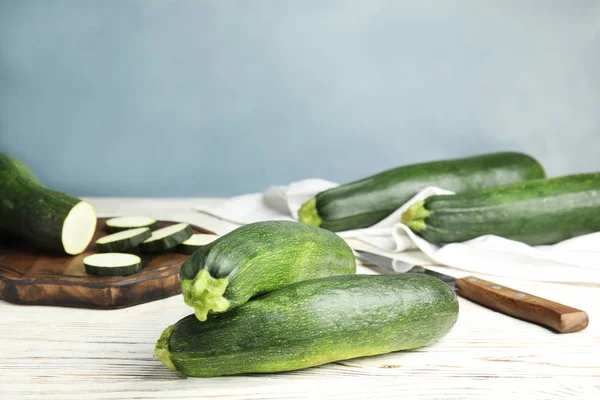 Fresh ripe green zucchinis on white wooden table against blue background, space for text — Stock Photo, Image