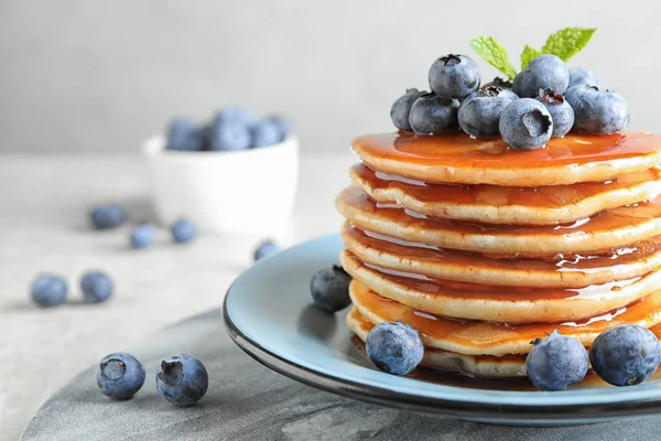Plate of delicious pancakes with fresh blueberries and syrup on grey table, closeup. Space for text — Stock Photo, Image