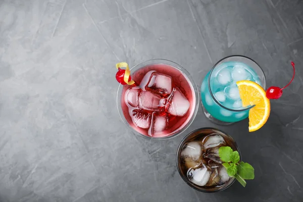 Gustosi cocktail rinfrescanti in bicchieri sul tavolo di pietra grigia, posa piatta. Spazio per testo — Foto Stock