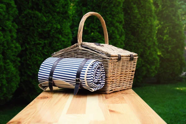 Rieten picknickmand met deken op houten tafel in Park — Stockfoto