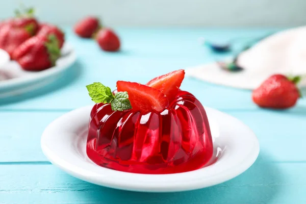 Delicious red jelly with strawberry and mint on light blue wooden table — Stock Photo, Image