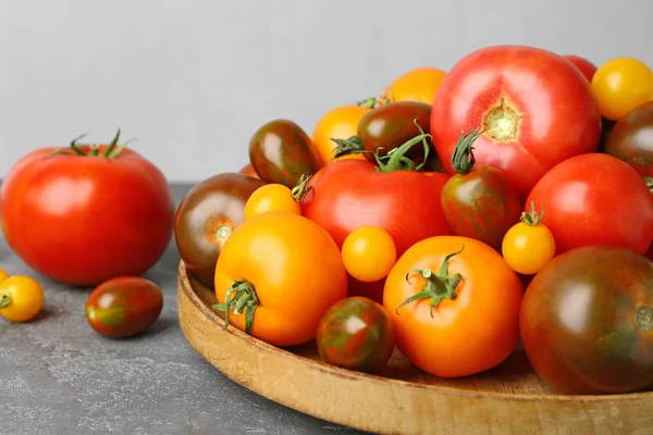 Muchos tomates maduros frescos en la mesa gris —  Fotos de Stock