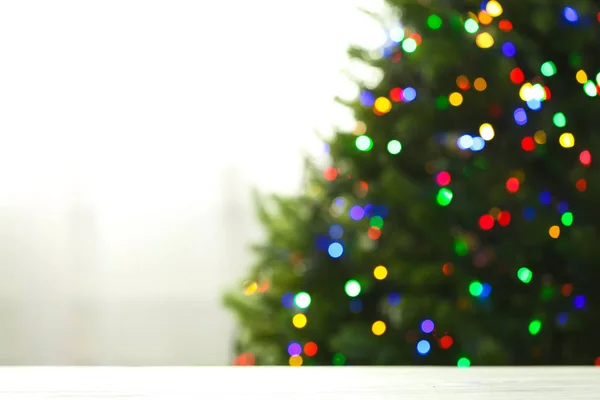 Tavolo vuoto e abete sfocato con luci di Natale colorate su sfondo, effetto bokeh. Spazio per il design — Foto Stock