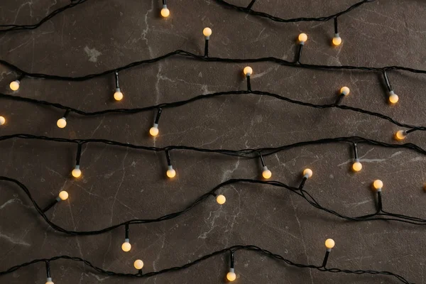 Glowing Christmas lights on grey marble background, top view — Stock Photo, Image