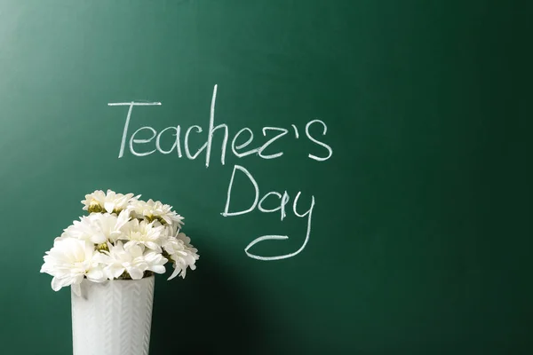 Váza virág közelében zöld palatboard felirattal Teacher 'S Day. Szóköz a szöveghez — Stock Fotó