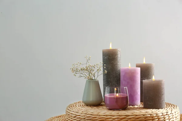 Velas diferentes na mesa de vime contra fundo cinza claro. Espaço para texto — Fotografia de Stock