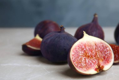 Mavi arka plan, closeup karşı açık gri mermer masada lezzetli olgun incir. Metin için alan