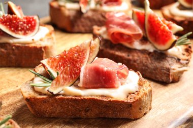 Krem peynir, prosciutto ve incir ile Bruschettas ahşap tahta, closeup servis