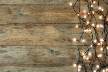 Ahşap arka planda parlayan Noel ışıkları, üst görünüm. Metin için alan