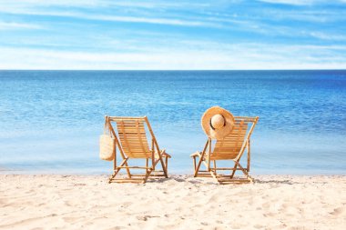 Denize yakın kumlu plajda ahşap şezlonglar