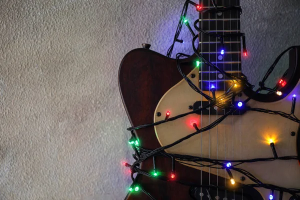 Gitaar met kleurrijke lichten op grijze stenen achtergrond, ruimte voor tekst. Kerst muziek — Stockfoto