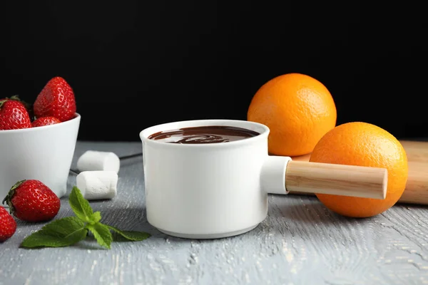 Fonduetopf mit Schokolade, Früchten und Eibisch auf grauem Holztisch — Stockfoto