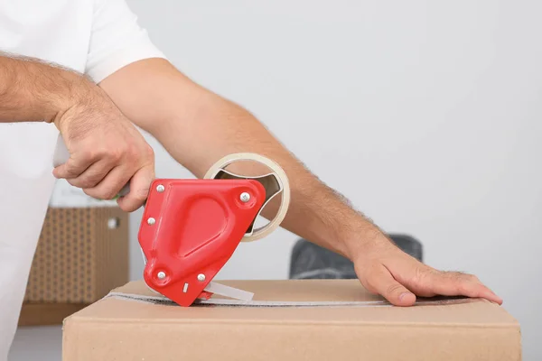 Trabajador joven empacando caja de cartón en la habitación, primer plano. Servicio móvil — Foto de Stock