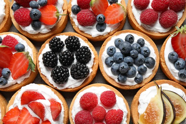 Many different berry tarts on table, top view. Delicious pastries