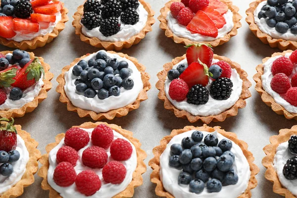 Many different berry tarts on table. Delicious pastries