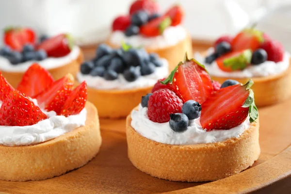 Houten plaat met verschillende bessen taartjes. Heerlijke gebakjes — Stockfoto