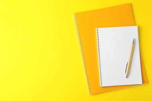 Quaderni e penna su sfondo giallo, vista dall'alto — Foto Stock