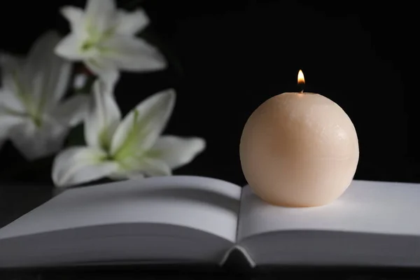 Κάψιμο κερί, βιβλίο και λευκά κρίνα στο τραπέζι στο σκοτάδι, κοντινά πλάνα με χώρο για το κείμενο. Σύμβολο κηδείας — Φωτογραφία Αρχείου