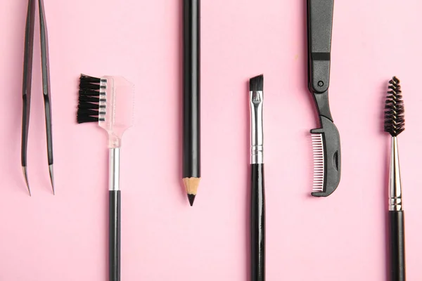 Set of professional eyebrow tools on pink background, flat lay