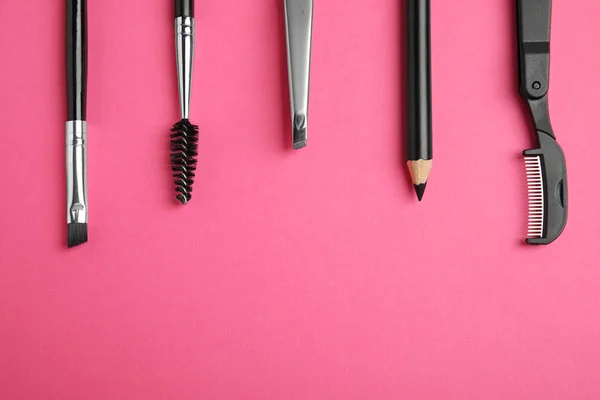 Set of professional eyebrow tools on pink background, flat lay. Space for text