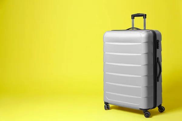 Stilvoller grauer Koffer auf gelbem Hintergrund. Raum für Text — Stockfoto