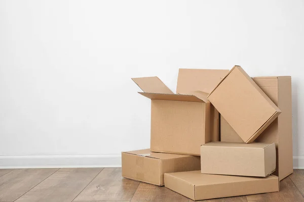 Pile of cardboard boxes near white wall indoors. Space for text — Stock Photo, Image