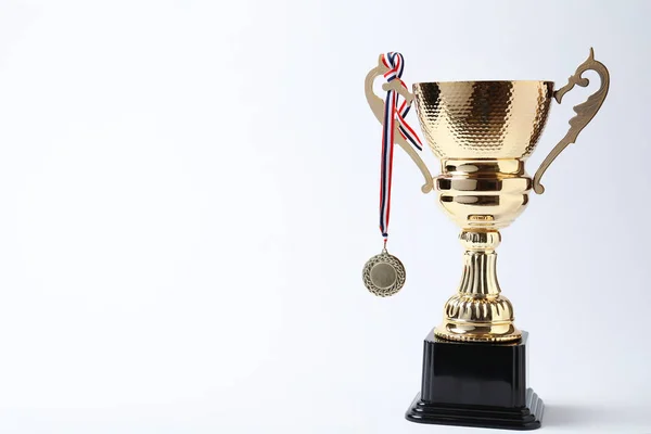 Taza de trofeo dorado brillante y medalla sobre fondo blanco —  Fotos de Stock