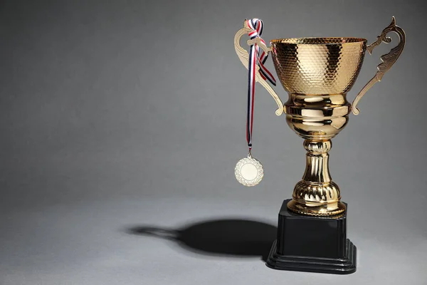 Gouden trofee beker en medaille op grijze achtergrond. Ruimte voor tekst — Stockfoto