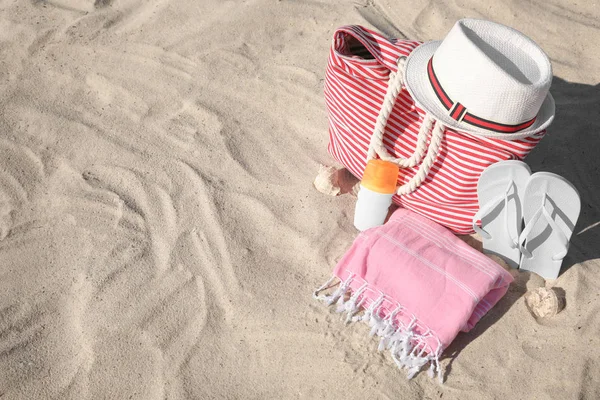 Elegantes accesorios de playa en la orilla del mar de arena, espacio para el texto — Foto de Stock