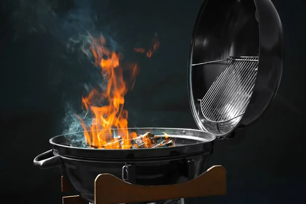 Новий сучасний гриль для барбекю з палаючими дровами на темному фоні — стокове фото